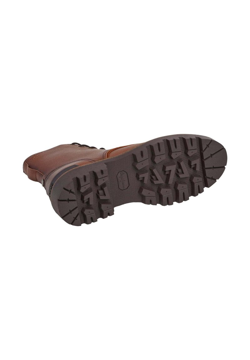 Bota de cuero marrón con una suela de goma resistente. La suela presenta surcos profundos para mayor tracción y una ligera curva en la punta para un diseño funcional.