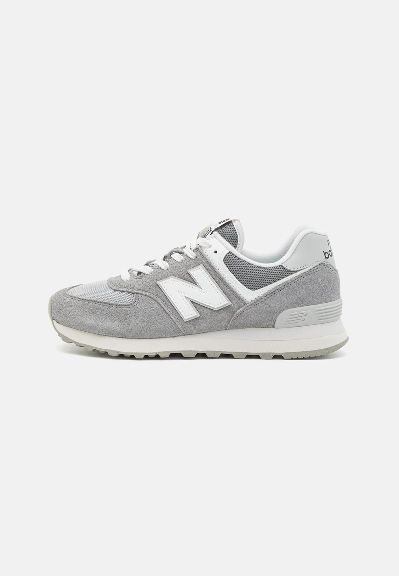 Baskets New Balance grises et blanches avec des panneaux en daim et en mesh, des lacets blancs et une semelle en caoutchouc texturée, vues de profil sur un fond blanc.