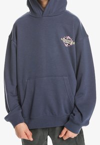 Námořnická modrá mikina s kapucí vyrobená z měkké tkaniny, s klokankou, šňůrkovou kapucí a barevným grafikou na hrudi.