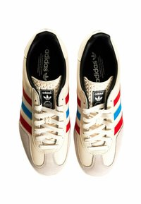 Krém színű bőr Adidas sportcipők piros és kék csíkokkal, fekete belsővel, fehér fűzővel és világosszürke velúr orrkapoccsal.