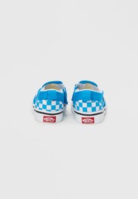 Μπλε παπούτσια τύπου slip-on με καρό ύφασμα και λευκές σόλες, με κόκκινο λογότυπο στη φτέρνα και εσωτερικό με επένδυση για άνεση.