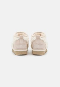 Botas de tobillo color crema con parte superior de lana texturizada, acentos de ante y suela de goma; cuenta con una lengüeta en la parte trasera para facilitar su uso.