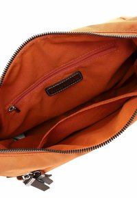 Interior view of an orange zippered bag showing a small inner zip pocket and fabric compartments inside.