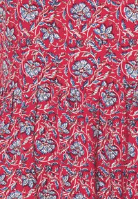 Tessuto rosso con un motivo floreale caratterizzato da fiori blu e bianchi, accentuato da foglie verdi, e una texture morbida con dettagli arricciati.