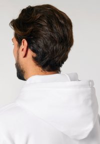 Felpa bianca con una vestibilità comoda, dotata di un ampio cappuccio e di un tessuto morbido e texturizzato. La vista è da dietro, evidenziando il collo.