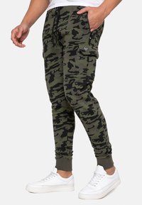 Camouflage joggerbukser i oliven og sort, lavet af blødt bomuldsblandingsmateriale, har tapered ben, elastiske manchetter og sidelommer til cargo.