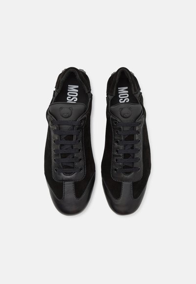 Black athletic shoes featuring a combination of smooth leather and soft suede, with a rounded toe, lace-up closure, and a bear logo accent.