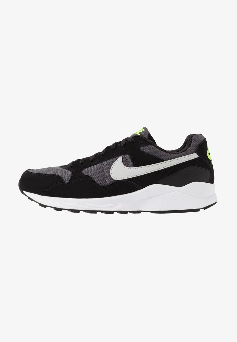 Sneakers Nike noirs et gris avec le logo Swoosh blanc, une marque vert fluo sur la languette et le talon, et une semelle blanche rembourrée.