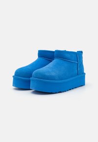 Bottines en daim bleu avec une semelle épaisse. Texture lisse, bouts ronds et tige basse. Pas de matériel ou d'accents visibles.