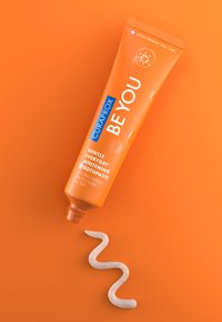 Tubetto arancione di dentifricio Curaprox BE YOU con tappo flip, etichettato come sbiancante delicato per l'uso quotidiano. Pasta bianca con macchie arancioni su uno sfondo coordinato.