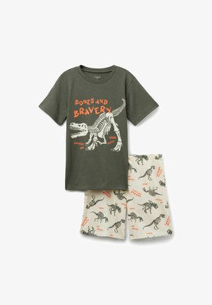Baumwoll-Schlafanzug bestehend aus einem olivgrünen T-Shirt mit einem Dinosaurier-Graphic und orangefarbener Schrift sowie einer creamfarbenen Shorts mit schwarzen Dinosaurier-Skelett-Mustern.