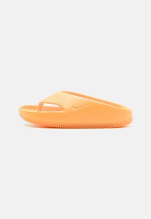 Oransje glidesandal med minimalistisk design, laget av glatt gummi-lignende materiale. Har en utskjært reim og mønstret såle for grep.