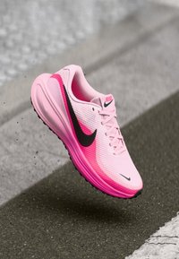 Nike hardloopschoen met een roze textielen bovenwerk en zwarte accenten, een ronde neus, een lichtgewicht ontwerp en een gevoerde zool.