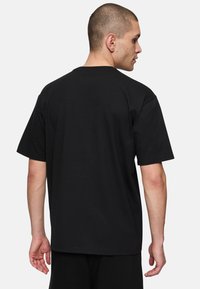Sort bomulds t-shirt med korte ærmer, rund hals og en afslappet pasform. Bagsiden har et enkelt design uden logoer eller mønstre.