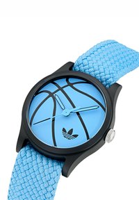 Basketbola tematika pulkstenis ar melnu korpusu, gaiši zilu ciparu, kas rotāts ar basketbola rakstu, un austo zilu siksnu ar sudraba kroņu.
