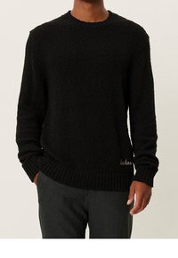 Czarny sweter z teksturowanej dzianiny z okrągłym dekoltem, z prążkowanymi mankietami i dołem, z małym haftowanym logo po dolnej stronie.