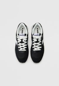 Schwarze Sport-Sneaker mit Obermaterial aus Mesh, weißen Schnürsenkeln und Logo auf der Zunge. Verfügt über eine abgerundete Zehenpartie und kontrastierende weiße Akzente an den Seiten.
