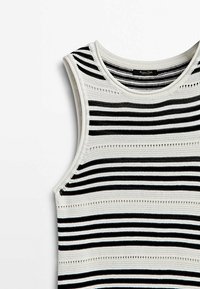 Haut sans manches en maille avec des rayures horizontales noires, blanches et beiges et de petits détails ajourés sur tout le tissu.