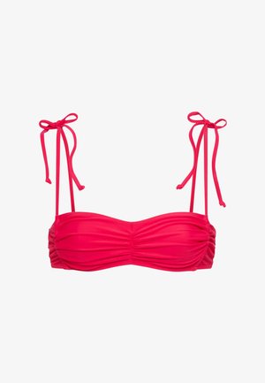 Sarkana bikini augšdaļa ar savērtu audumu un plāniem siksniņām, kas sasietas lokos uz baltas virsmas.