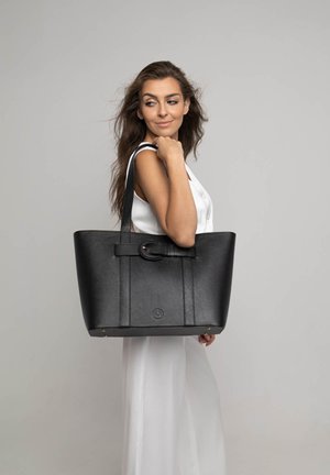 Borsa a tote nera in pelle con una finitura texturizzata, caratterizzata da un evidente dettaglio in metallo circolare e due lunghe maniglie piatte per il trasporto.