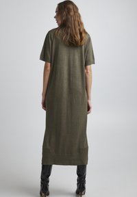 Robe vert olive, longueur genou, fabriquée en un matériau tricot doux. Dotée de manches courtes et d'une coupe décontractée, avec un ourlet droit en bas.