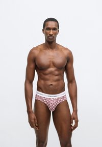 Męskie bokserki Calvin Klein w kolorze czerwonym i białym z geometrycznym wzorem, elastyczny pas z logo, dopasowany krój i gładka faktura.