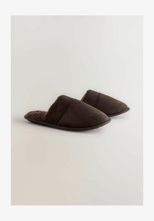 Bruine suède pantoffels met een zachte, donzige voering. Instapmodel, puntige neusvorm en minimale stiksels op het bovenwerk. Plat zool.