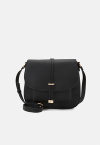 Sac en cuir texturé noir, à bandoulière, avec rabat de fermeture, sangle fine et deux accents en métal doré sur la sangle avant.