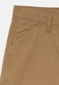 Brune stoffshorts med teksturert ribbestruktur, fem-lommestil og stingdetaljer langs sømmene og lommene.
