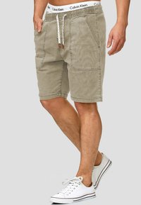 Khaki shorts met een elastische tailleband, trekkoord, twee voorkezen, licht gestructureerde stof, gestyled met witte sneakers.
