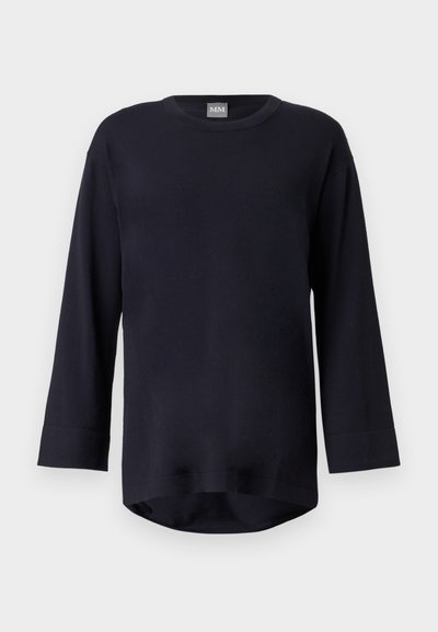 Chemise noire à manches longues avec col rond et ourlet légèrement incurvé, présentée sur un fond gris clair.