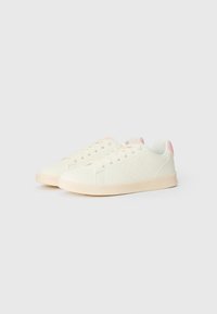 Sneaker bianchi realizzati in materiale liscio con un design perforato, dettagli rosa chiaro sul tallone e suola in gomma beige.