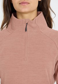 Hellrosa, weich strukturierter Pullover mit Viertel-Reißverschluss und hohem Kragen, ausgestattet mit einem schwarzen Zip-Puller am Hals, aus einem dezent melierten Stoff.