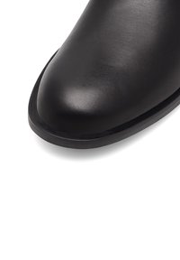 Stivaletto in pelle nera con punta arrotondata, texture liscia e una leggera lucentezza. Presenta una suola nera robusta. Nessun abbellimento visibile.