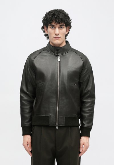 Μαύρο δερμάτινο bomber μπουφάν με ψηλό γιακά, μπροστινό φερμουάρ, πλαϊνές τσέπες και ραμμένες μανσέτες, διαθέτοντας λεία υφή και εφαρμοστή σχεδίαση.