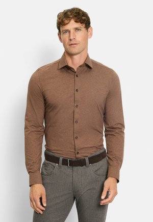 Braunes Langarmhemd mit Button-Down-Kragen und schwarzen Knöpfen. Kombiniert mit grauen strukturierten Hosen und einem dunklen Gürtel.