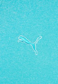 Turkos tyg med en texturerad yta har en vit broderad Puma-logotyp som visar en framträdande leaping cat-design centrerad.