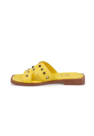 Geel schuifsandalen met een platte bruine zool, met een glad leren bovenwerk versierd met metalen studs en een kruislings ontwerp.