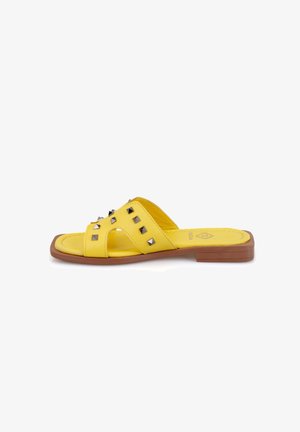 Geel schuifsandalen met een platte bruine zool, met een glad leren bovenwerk versierd met metalen studs en een kruislings ontwerp.