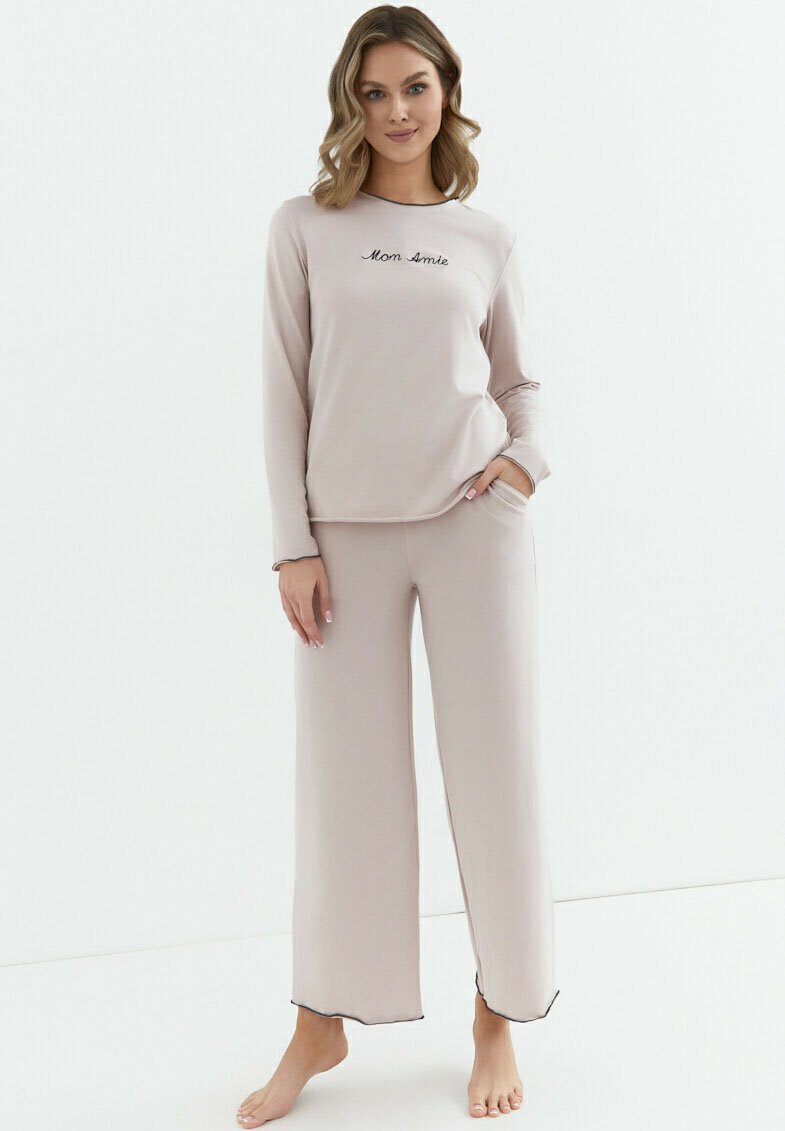 Komplet piżamowy z miękkiej beżowej tkaniny, z długimi rękawami i spodenkami o szerokich nogawkach. "Mon Amie" wyhaftowane na czarno na górze. Gładka faktura i swobodny krój.