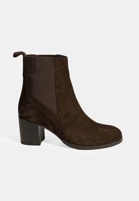 Bruine suede enkellaars met een gestapelde hak, elastische zijpanelen en geperforeerde accentdetails langs de bovenkant. Glad oppervlak overal.