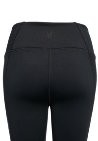 Svarta leggings med hög midja, med en diskret spindelmotiv, platta sömmar och en slät, elastisk tyg.