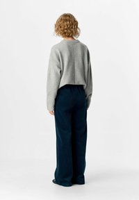 Pull gris court en tissu doux, associé à un pantalon large en velours côtelé bleu foncé. Design simple avec des poignets et une taille côtelés.