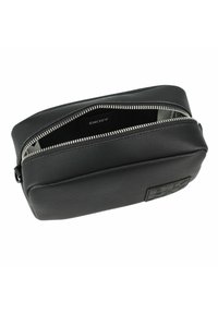 Pochette da toilette in pelle nera con chiusura a zip, superficie texturizzata e logo DKNY sul fronte. Interno foderato con un materiale più chiaro.