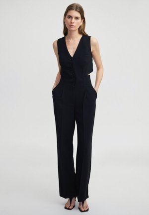 Black sleeveless jumpsuit with a V-neck, front button closure, and side pockets; features tailored fit and wide legs. Smooth fabric texture.