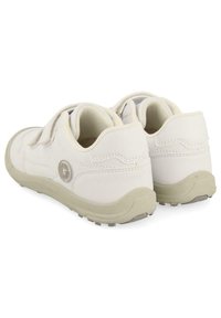 Chaussures blanches avec une tige en cuir lisse, un col rembourré, deux bandelettes Velcro et une semelle en caoutchouc gris clair, arborant un accent de logo subtil.