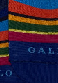 Calzini a righe con colori blu, arancione, verde, giallo e rosso con texture a coste. Testo blu "GALLO" su una sezione blu scuro.