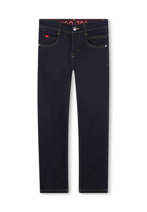 Jeans en denim bleu foncé avec des coutures contrastantes jaunes, cinq poches et un bouton de fermeture en métal argenté. Présente une étiquette de marque rouge sur la taille.