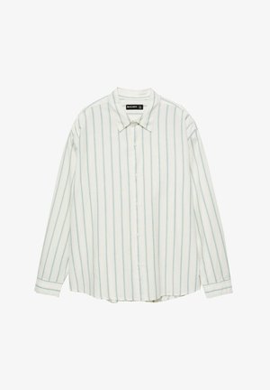 Cămașă albă cu mânecă lungă, cu dungi verticale albastre. Prezintă o rever, o deschidere cu nasturi și o croială lejeră. Fabricată dintr-un material ușor.