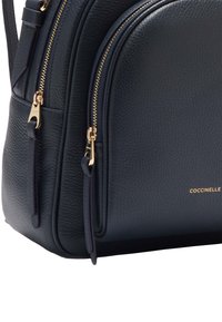 Námořnická kožená kabelka s textura povrchem, dvěma zipovými přihrádkami a akcenty zlaté barvy. Obsahuje logo potištěné zlatem.